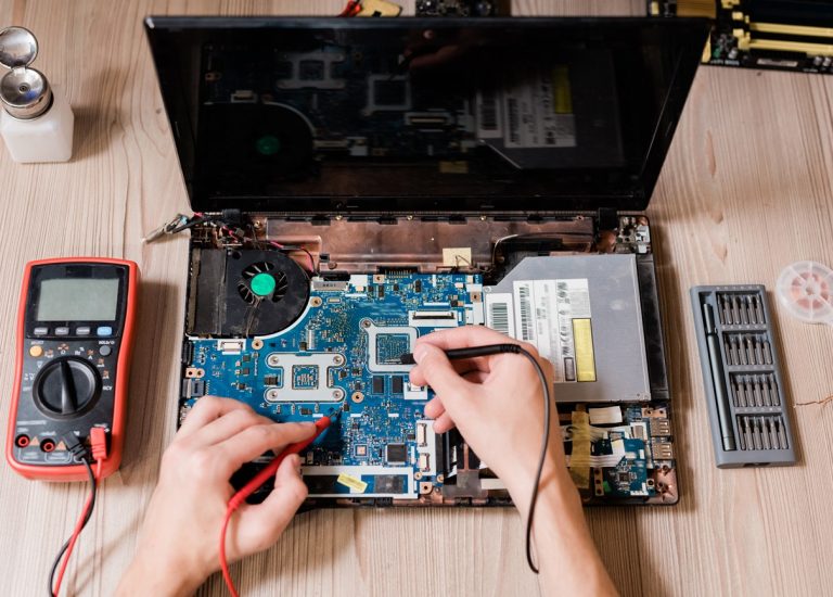 Hands of contemporary technical repairman using two small soldering-irons to repair broken laptop